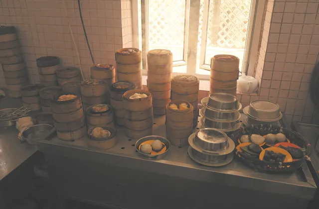 Stacks of bamboo dim sum steamers on a counter by a window