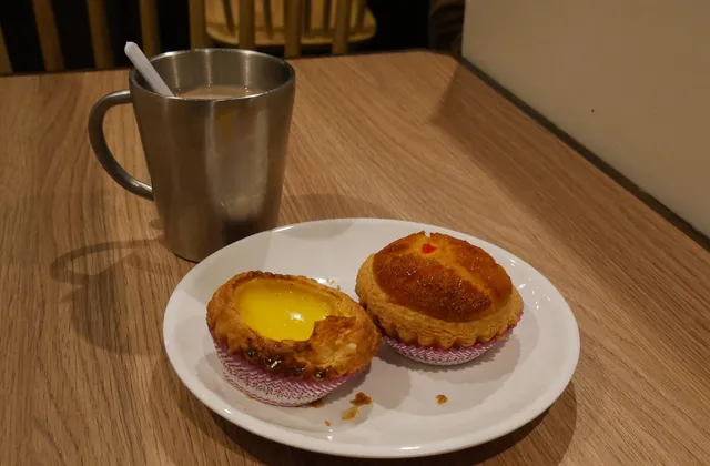An egg tart and a cup of milk tea on a café table