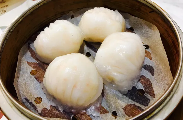 Four translucent shrimp dumplings in a bamboo steamer