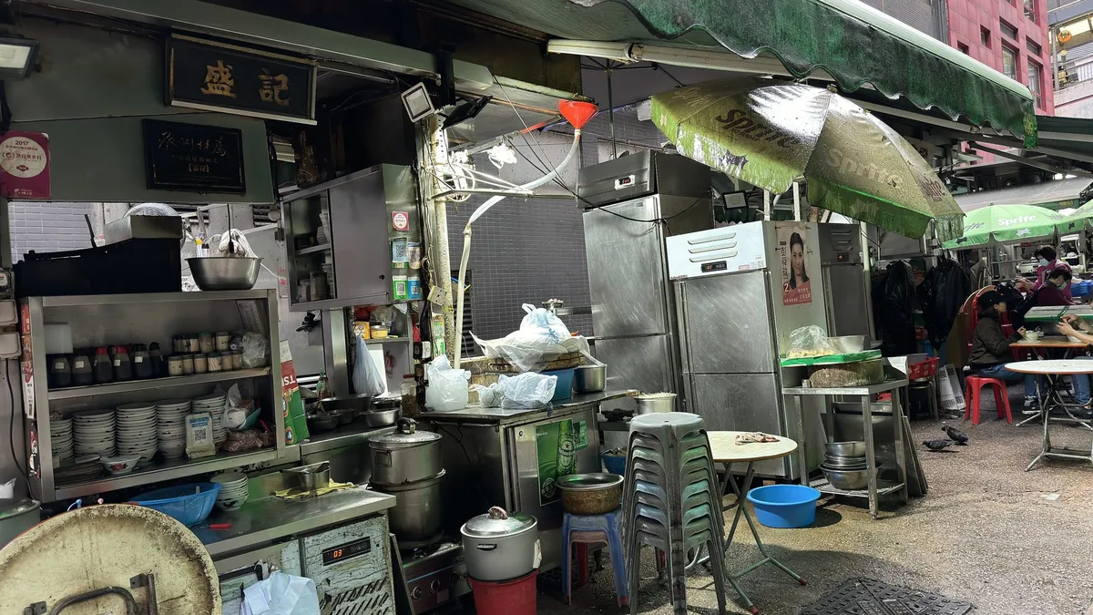A dai pai dong kitchen on Stanley Street with steel counters, stools and green awnings