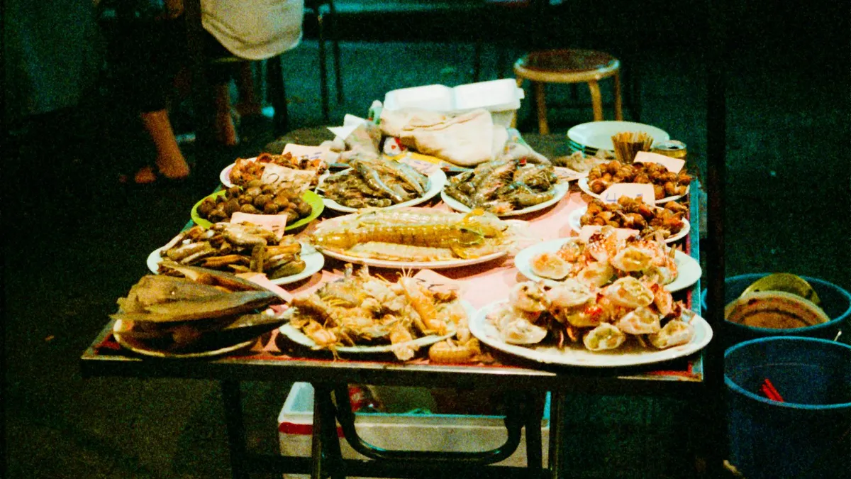 A table of seafood dishes at night, from steamed fish to shellfish