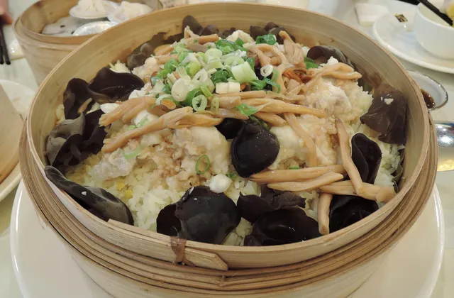 Steamed fish topped with ginger and spring onion in a bamboo steamer
